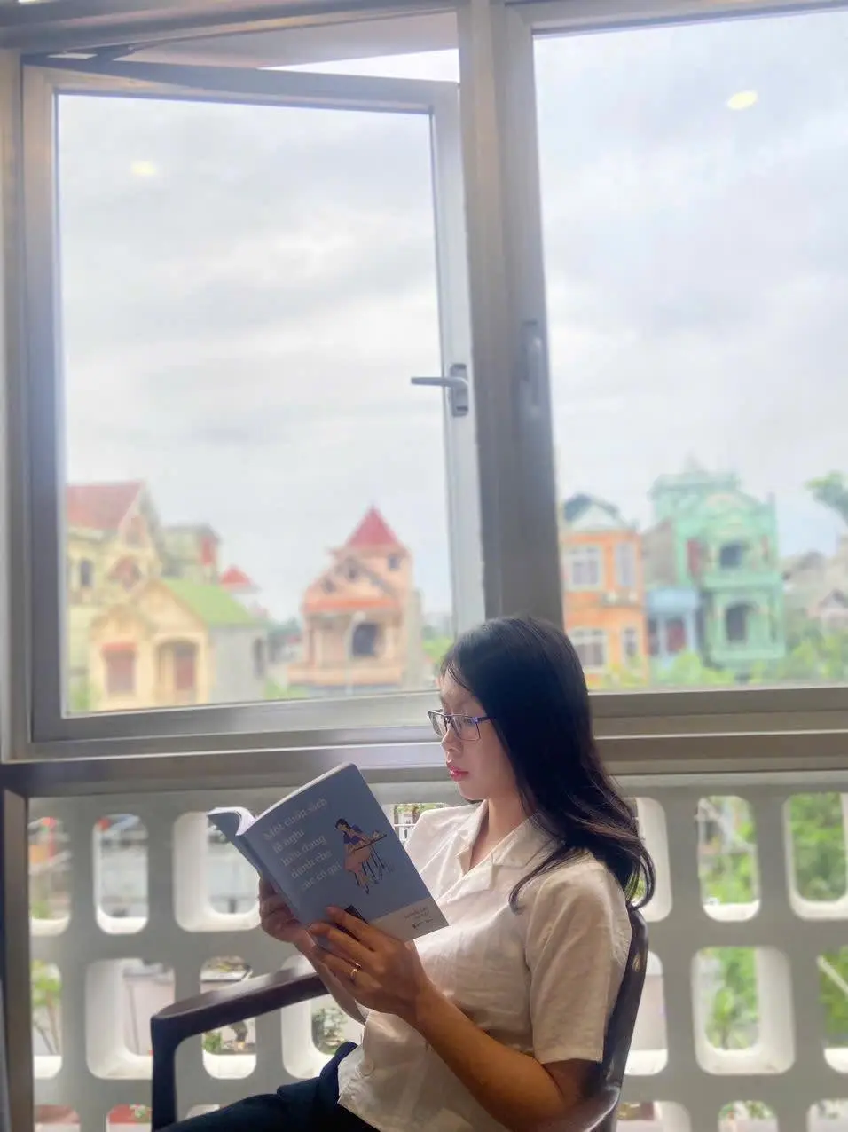 Emma đọc sách bên khung cửa sổ